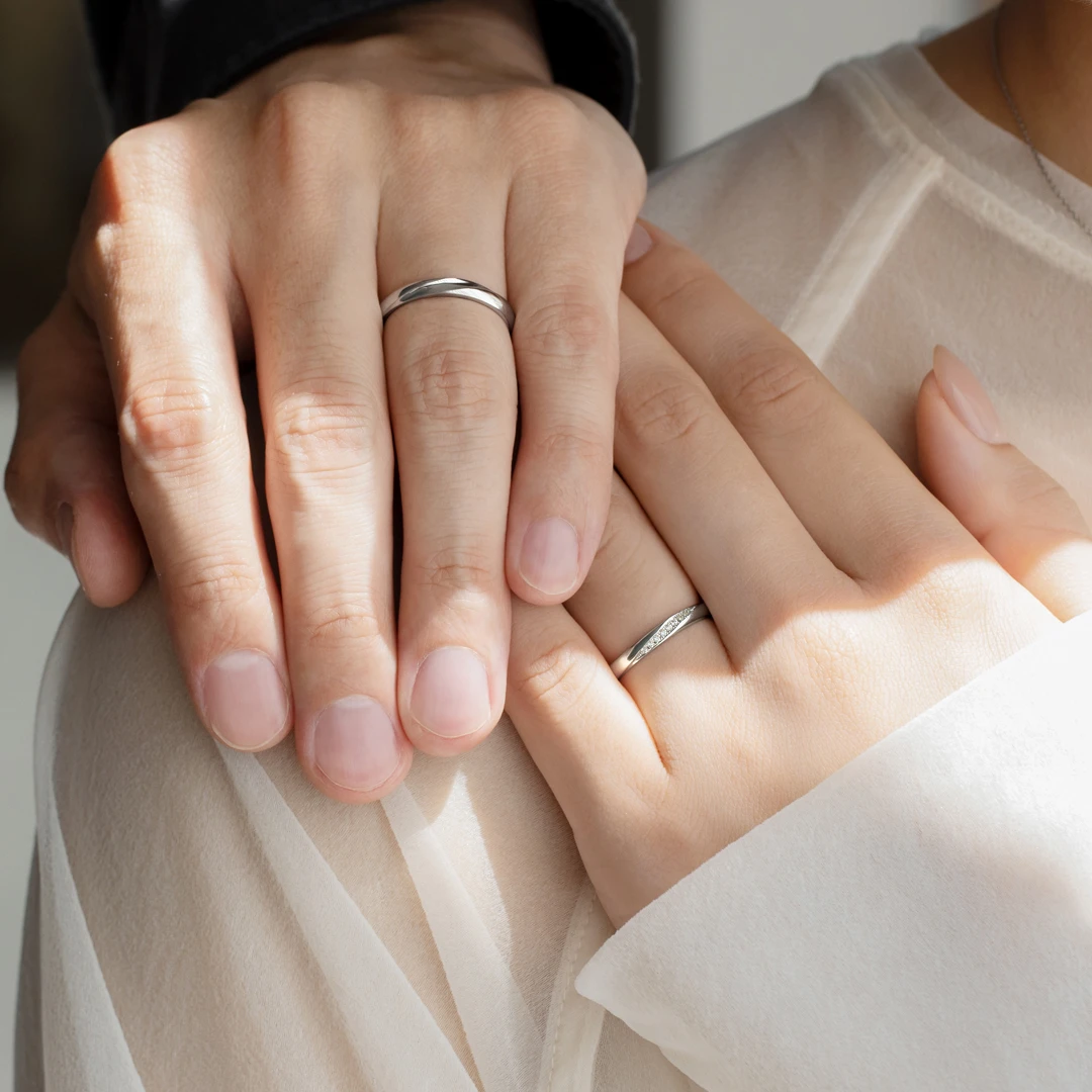 シンプルな中にアクセントを加えて流れるリボンのフォルムが二人を繋ぐオーバルストレートリング